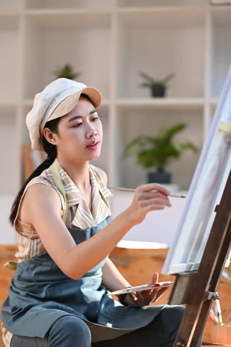 Pretty female artist painting on canvas in her art studio.