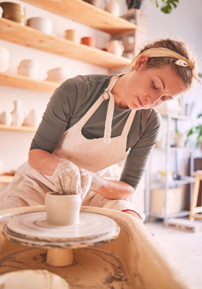 Woman, clay artist and pottery wheel for sculpture design, creative manufacturing and expert focus
