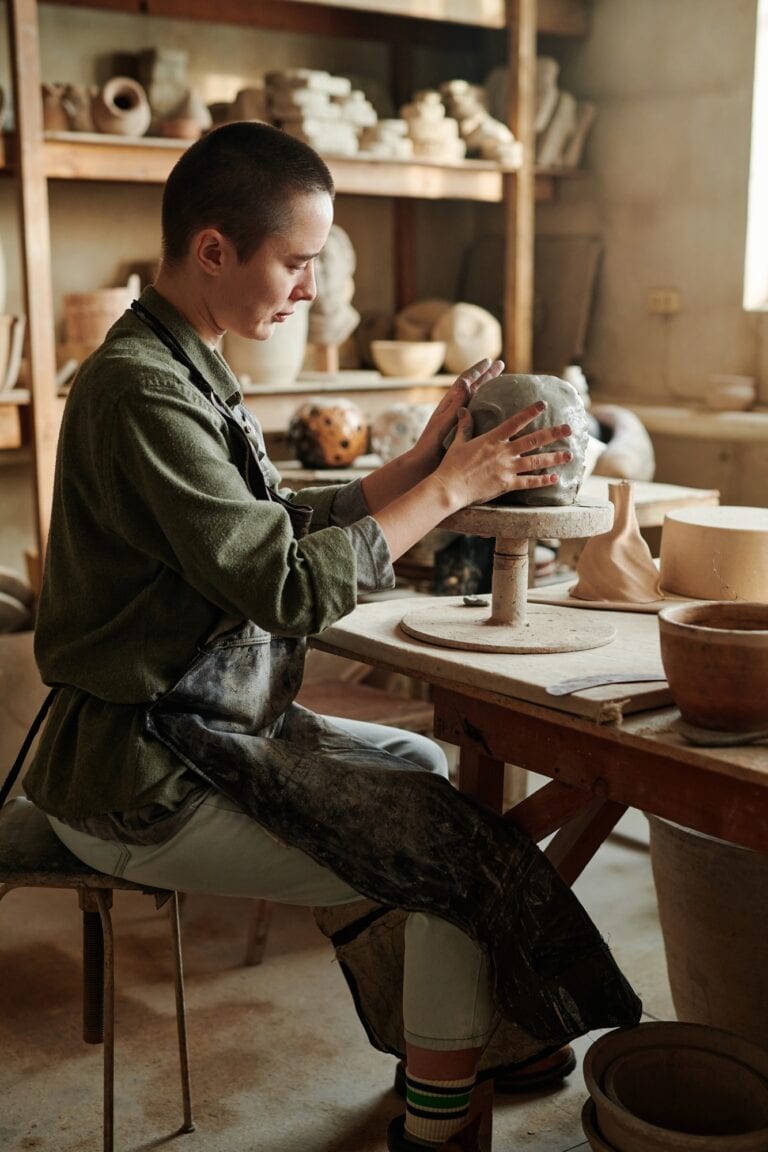 Woman making vase from clay